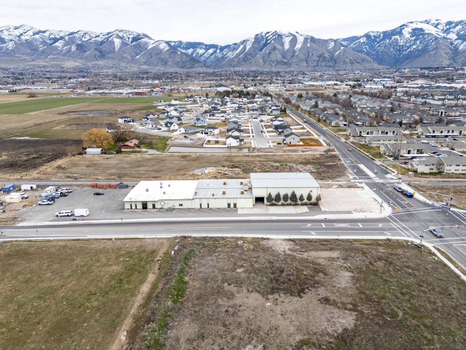 Aerial view of Cache Valley with new homes, a warehouse, and the mountains behind